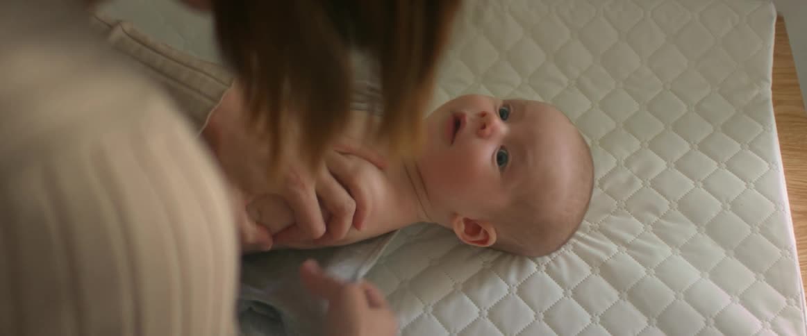 A woman laying a baby down on a changing pad