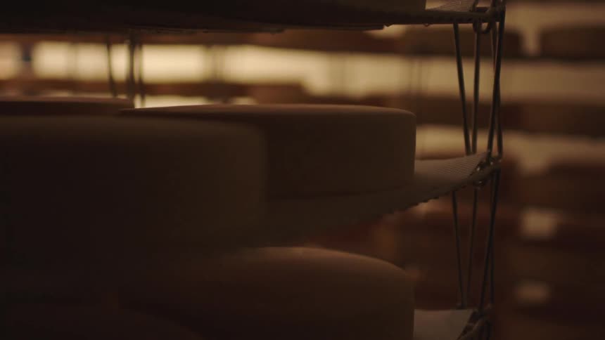 Cakes sit on lined shelves in dim area lit by light coming through blinds