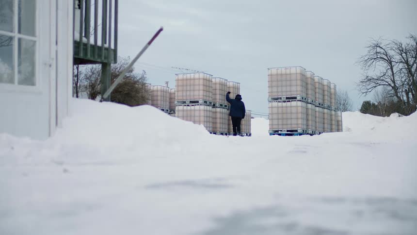 Rows of stock tanks on top of each other as a person goes up to them and hit them with his hand