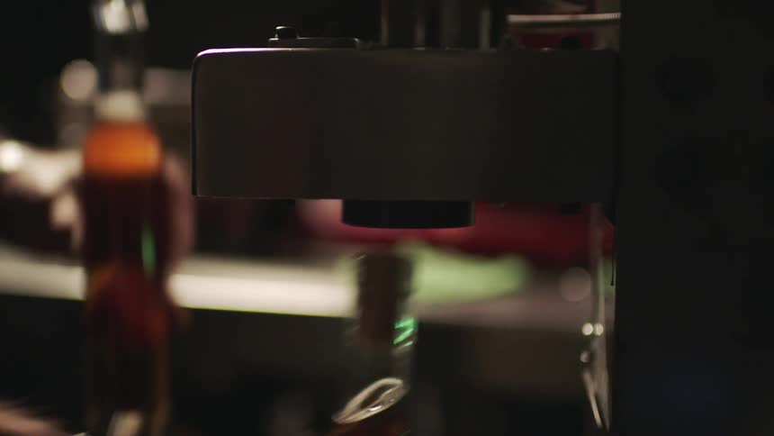 A mans hand is shown corking wine bottles with a corking machine