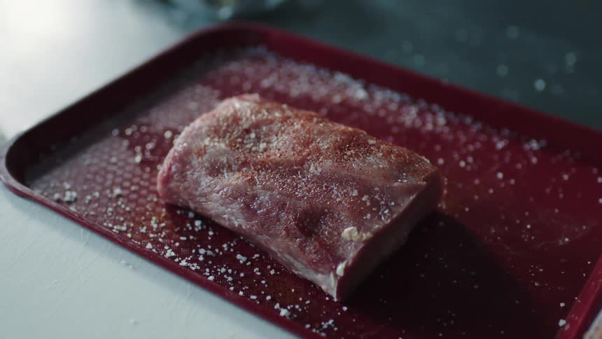 Frozen meat sits on red tray on white counter