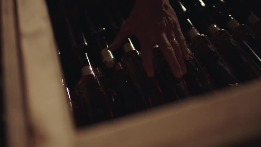 Bottles lined up in a drawer as a person places another bottle on top of them