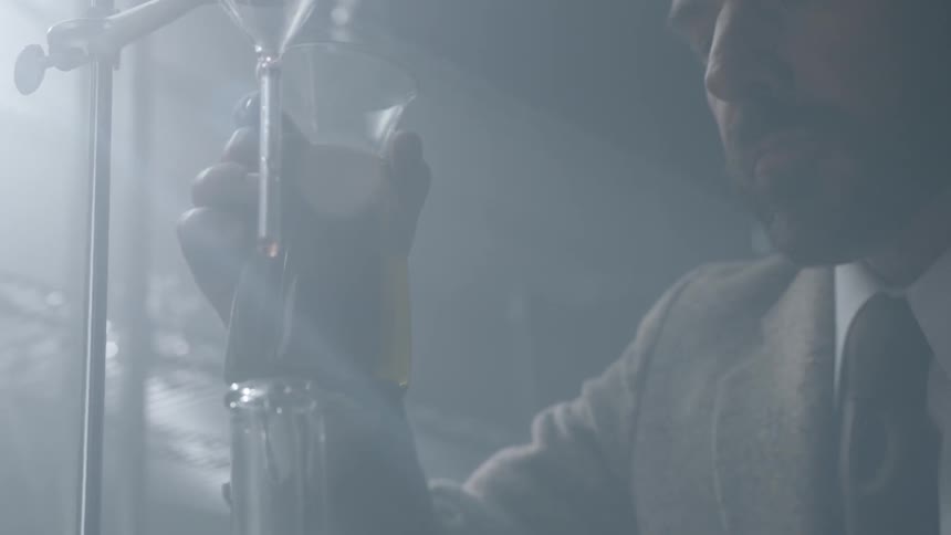 Man pours liquid into a flask in a laboratory