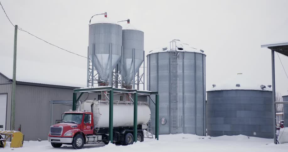 Semi tanker parks under tanks at factory to load