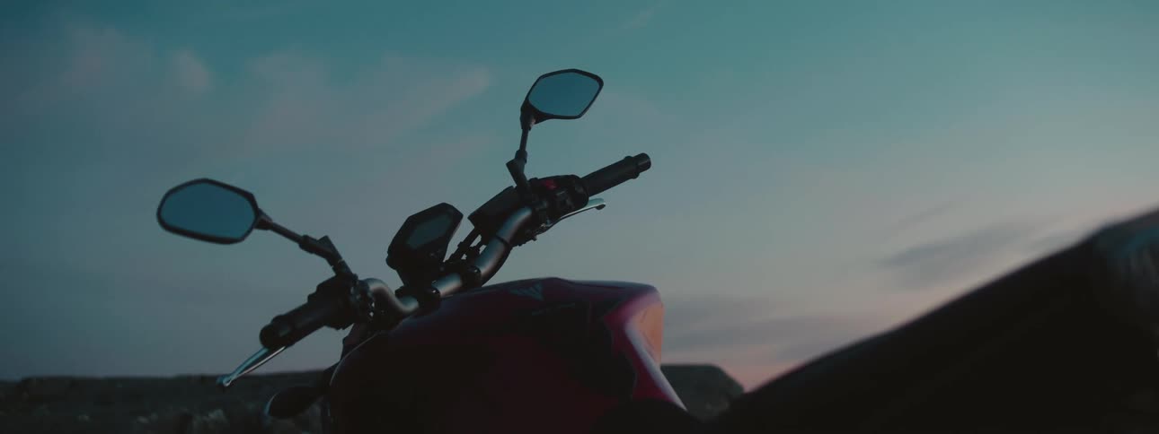 Panoramic view of a hill and the sky at sunset with a motorcycle in the foreground