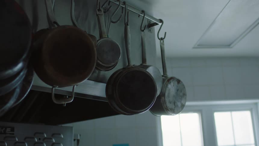Pots and pans hanging overhead from metal rod in a kitchen