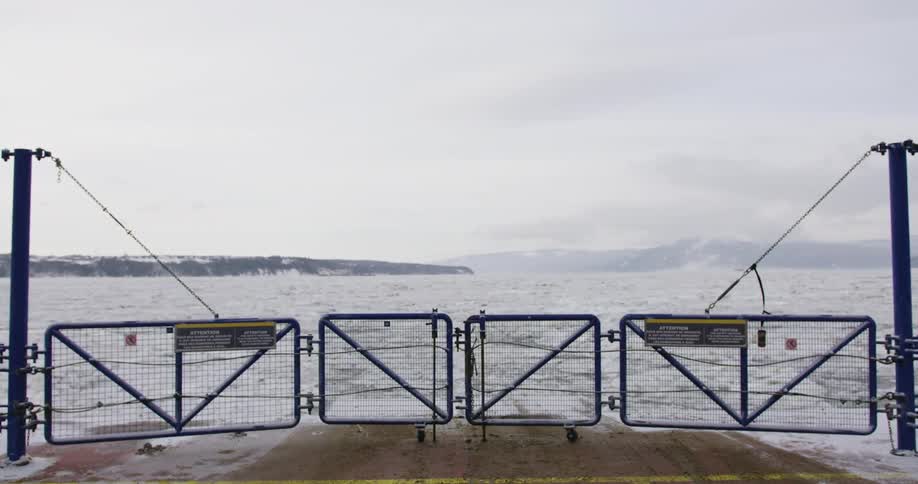 Man walking to stern of boat moving through icy waters toward horizon