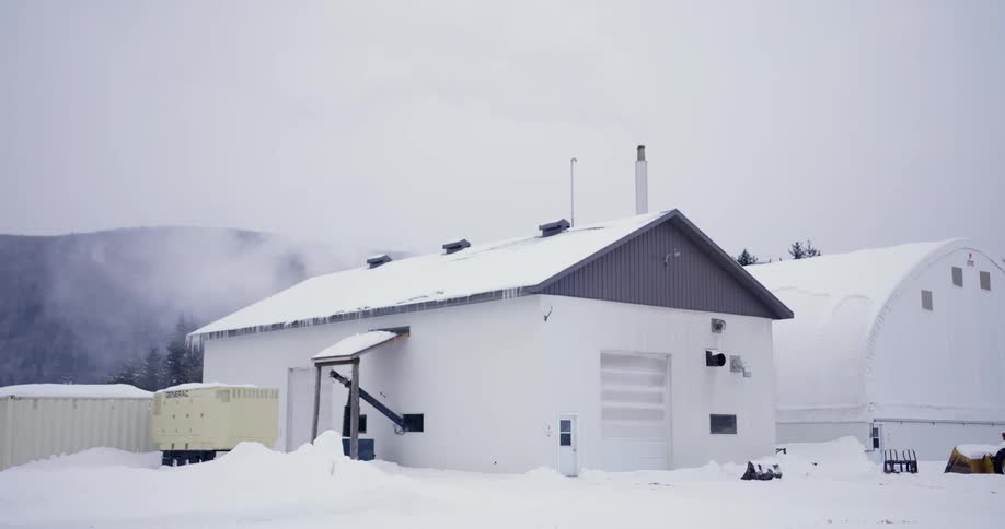 The outside of two white buildings in winter with snow on the ground