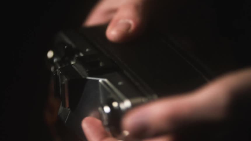 An up close of a camera and film as a person closes the back of the camera
