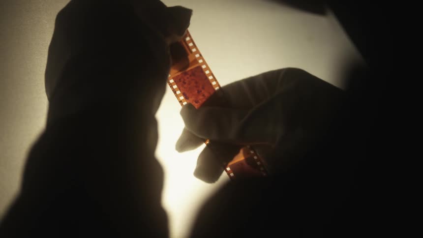Photographer wearing gloves wiping off a negative slide