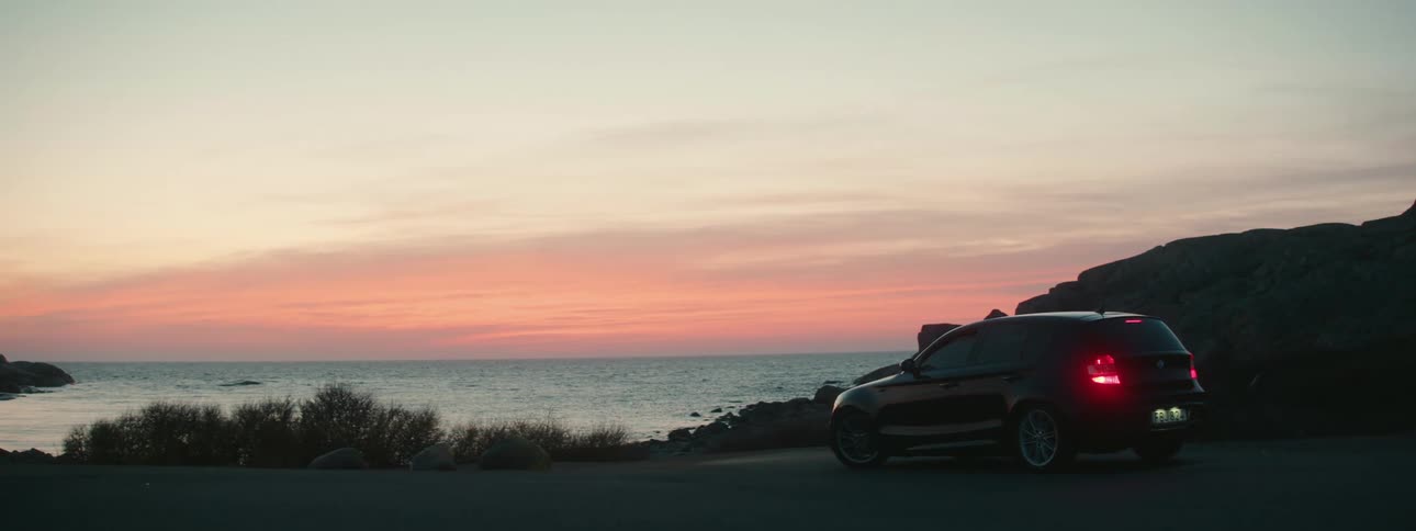 Suv stopped on road in front of beach watching sunset over the water