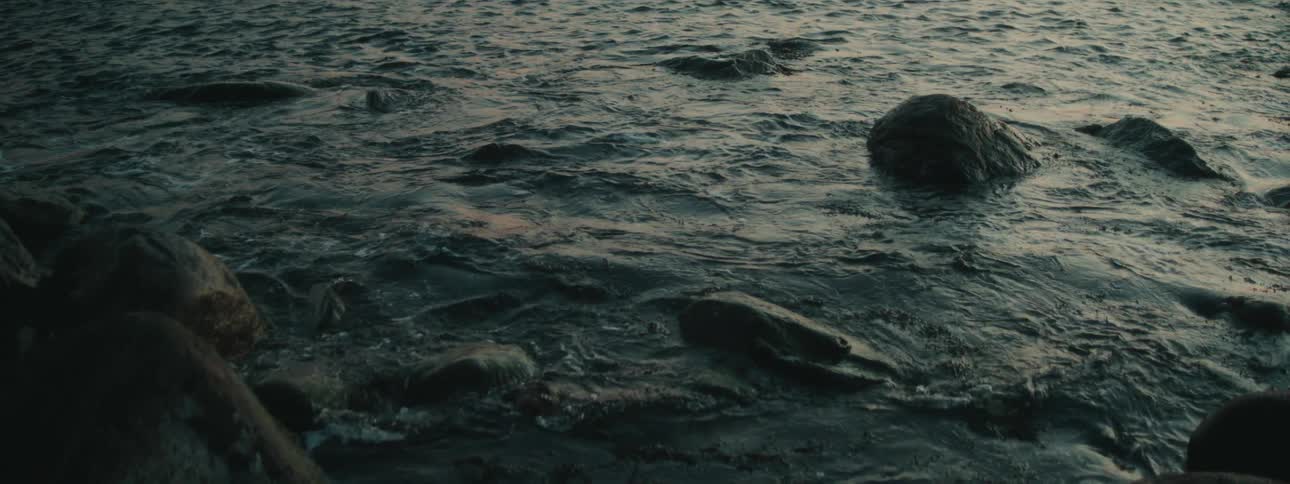 Waves splash over rocks in the water along the shoreline