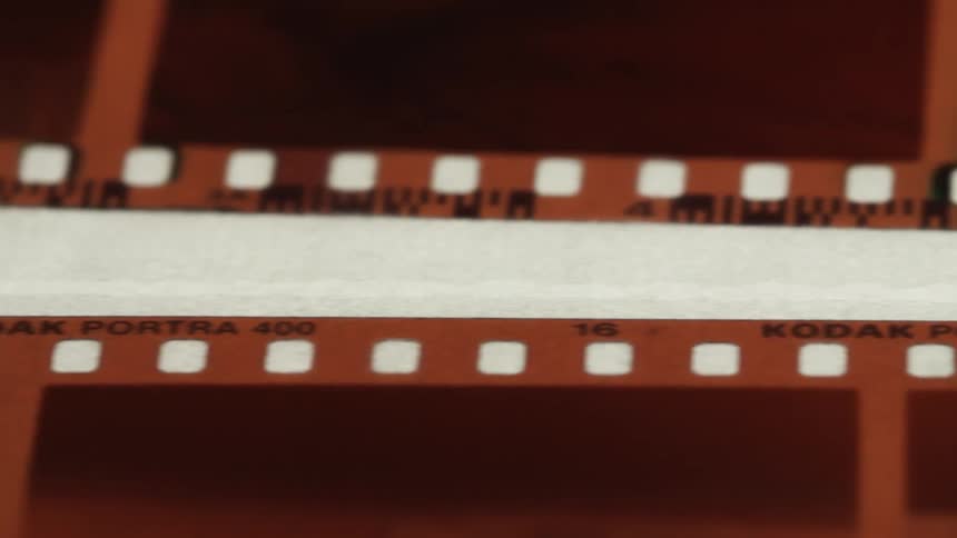 Extreme close up of a pair of strips of film negative over a backlit surface