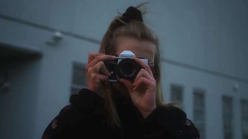 Blonde woman with black sweater photographing with camera and taking pictures, close-up, creative process, lifestyle