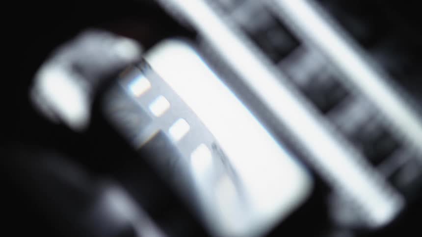 A person is looking at film with a magnifying glass