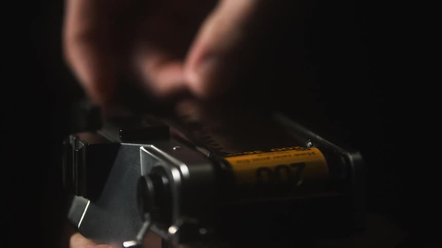 An up close of a film camera as a person rolls the film in the camera