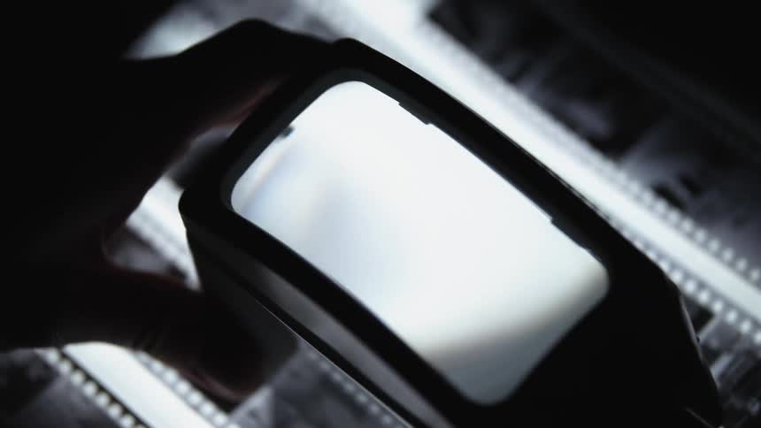 Close-up of film reeling through negatives, pictures, analog photography, darkroom mood
