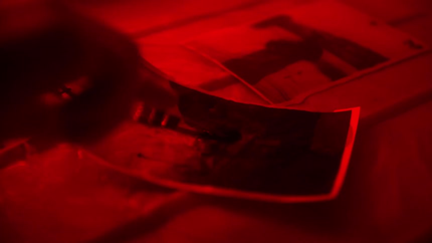 Close-up of film picture developing tank in red light, analog process
