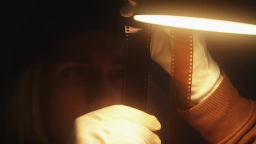 Close up of a person holding film negative in his hands with gloves on in the darkroom