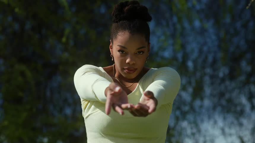 A woman wearing a yellow shirt moving her arms and body around
