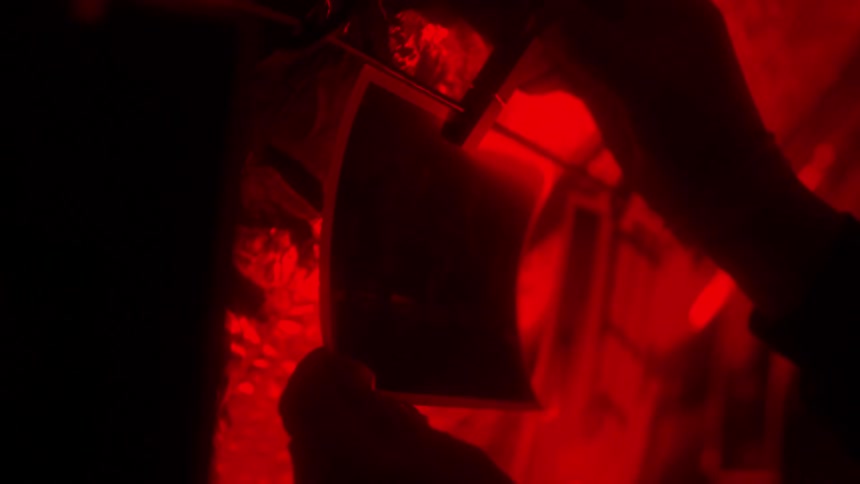 Film developing in darkroom under red light, analog photography processin