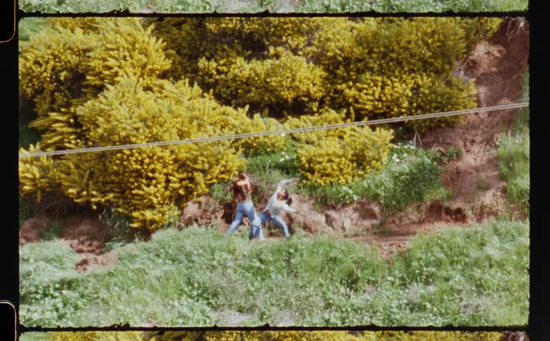 Two young females dance together while outside while surrounded by trees and grass
