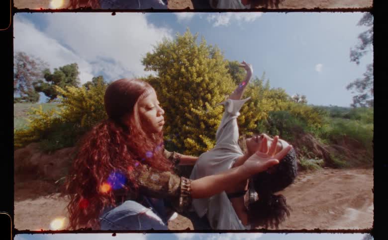 Two female dancers move through poses on dirt road
