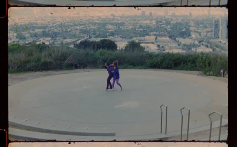 Two women dancing and moving around on a concrete platform