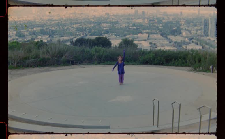 Two women dance on a stage with a city skyline behind them