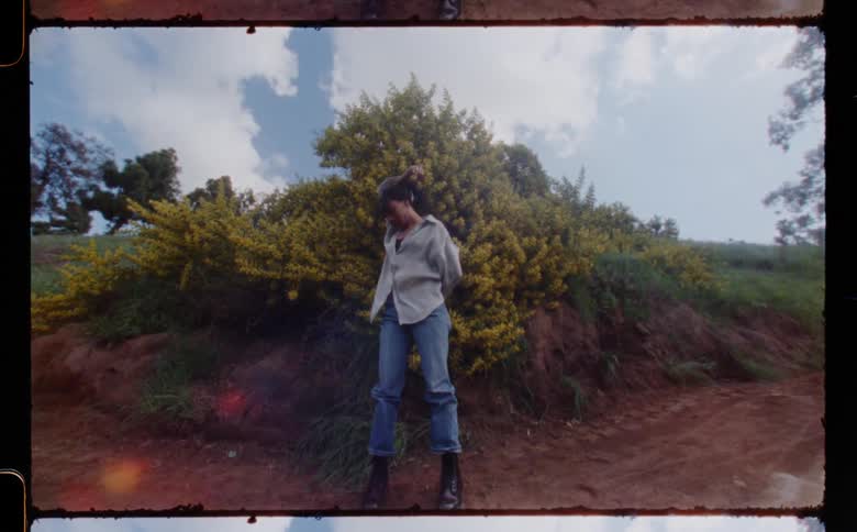 A woman standing up and dancing and then walking away on a dirt path