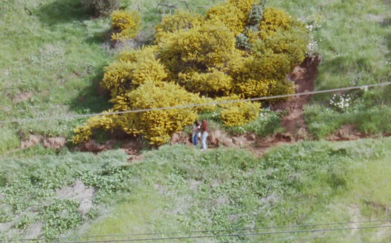 Two teenage girls as dancing on a mountainside hill near trees