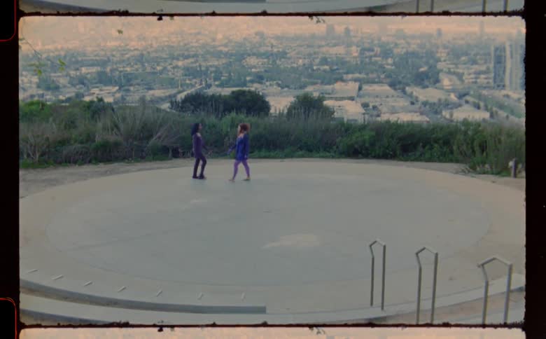Two women walking around a concrete circle in opposite directions