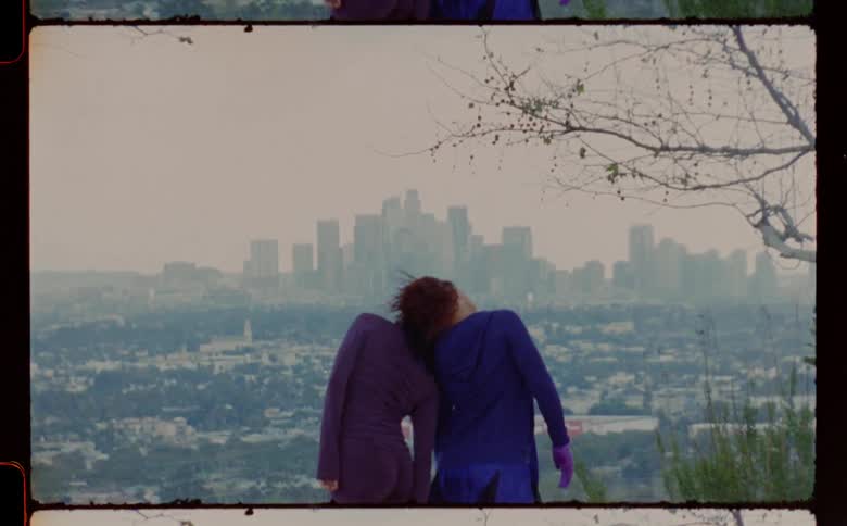 Two young woman do an interpretative dance at a location with views of downtown