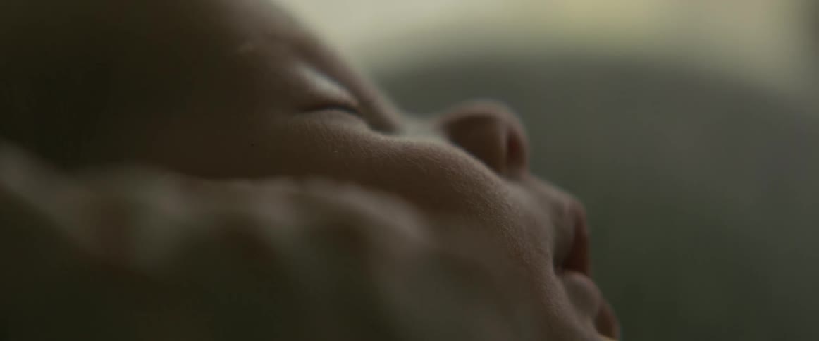 Close up of the face of a newborn baby being held by his mother