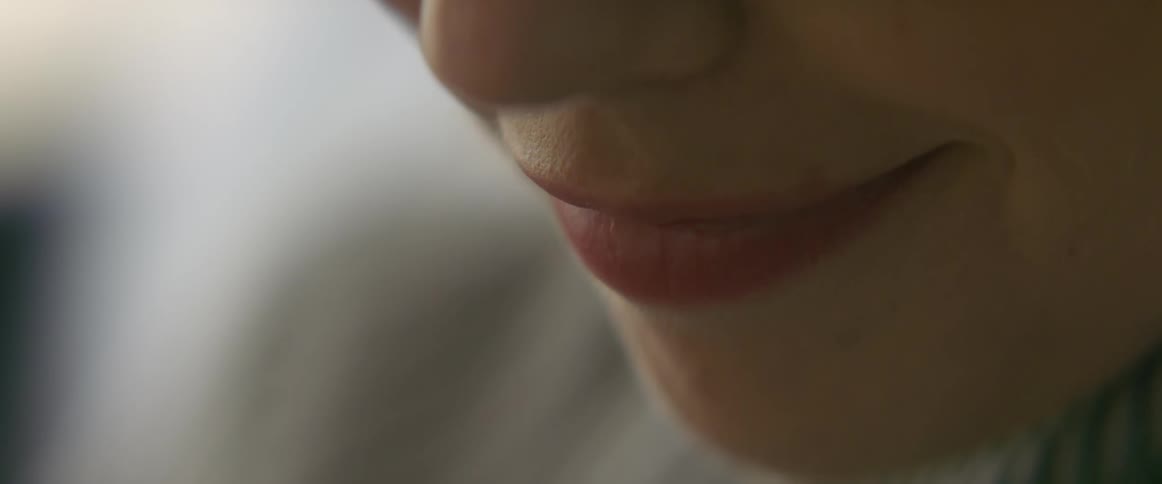 The mouth of woman curves slowly as she smiles