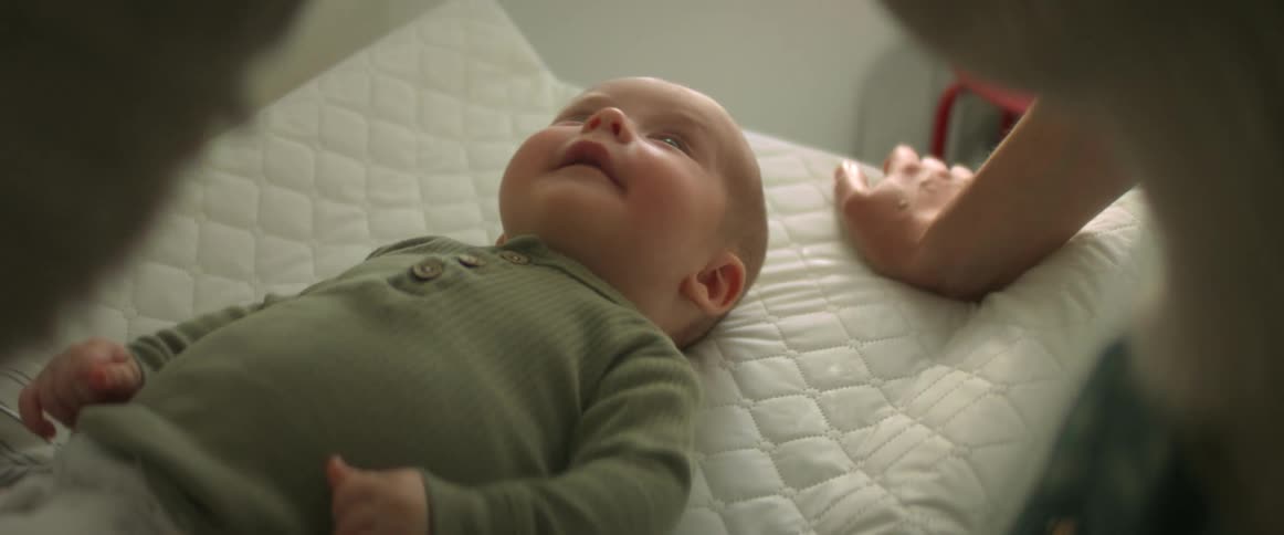 Mother ticking the nose of her newborn son in a bed at home