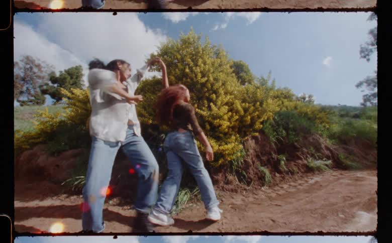 Young couple standing on a dirt road in the countryside dancing caught on vintage film