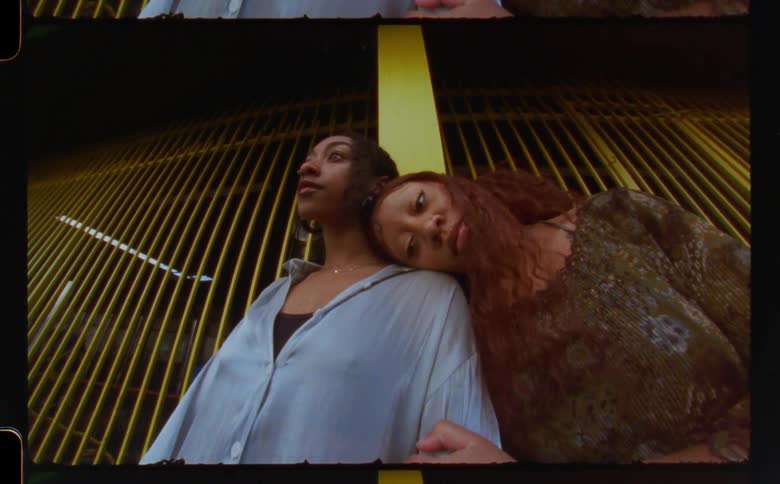 Mother and daughter standing together in front of parking garage gate in city