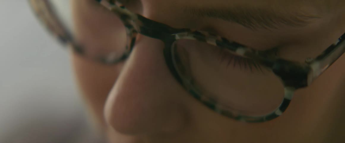 Close up view of a the face of woman wearing glasses as she turns her head