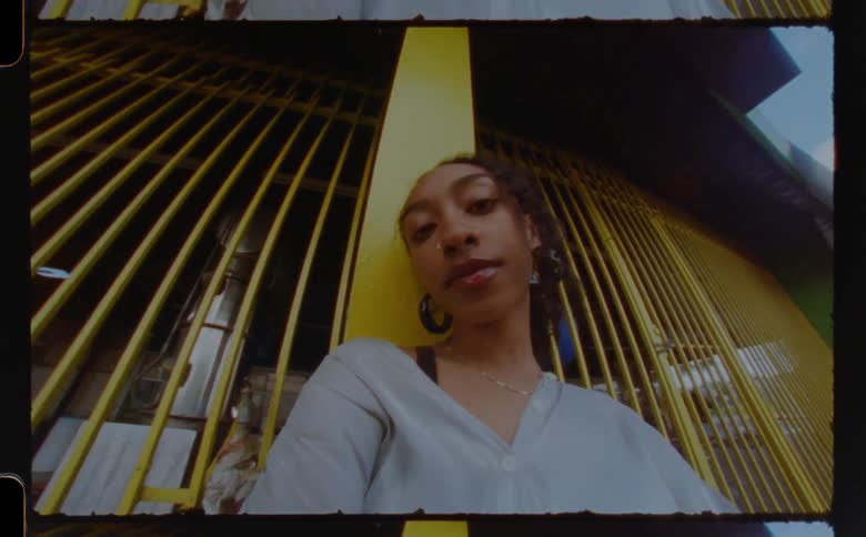 A close up of a womans face leaning against a yellow pole