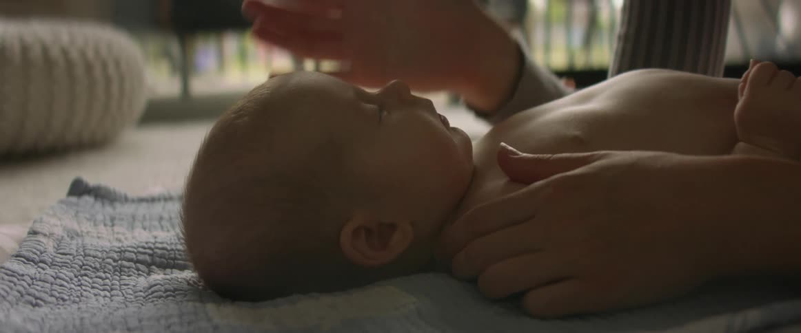 A woman leans over her baby while sitting on the floor