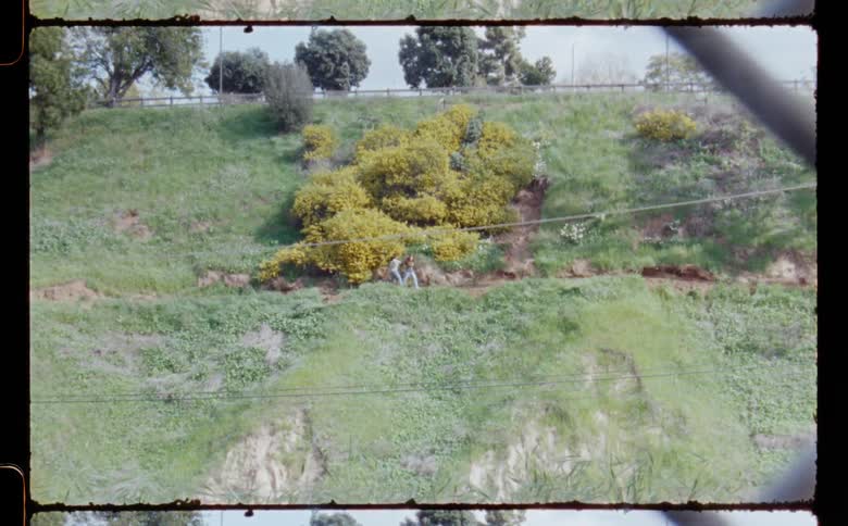 Two teenage girls are dancing on a mountainside hill near trees