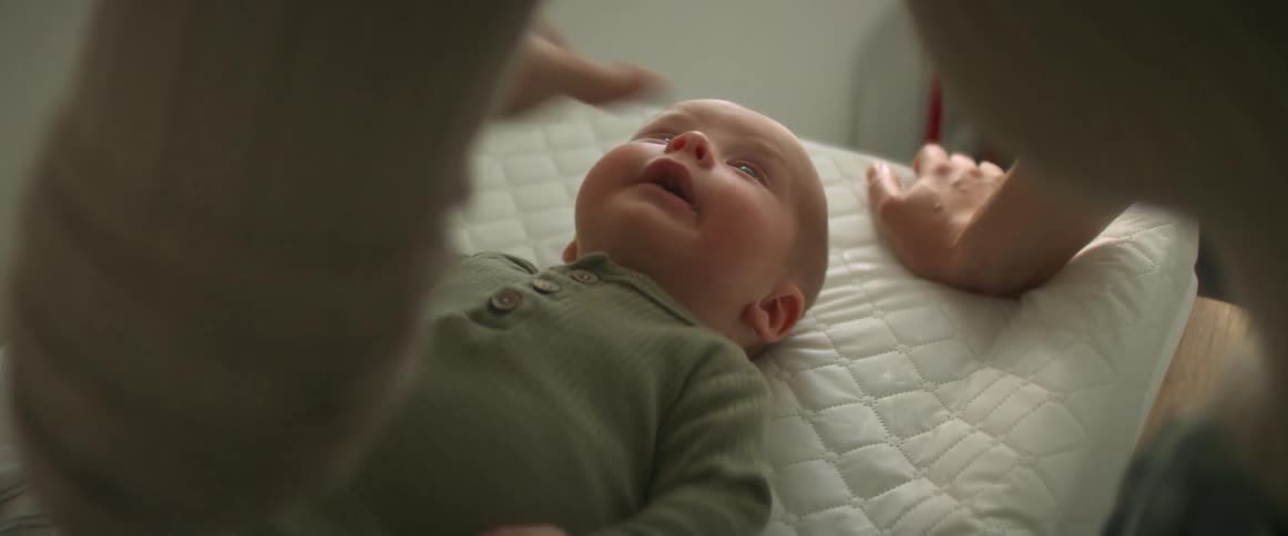 A woman is leaning over her baby playing as they move their arms and smile