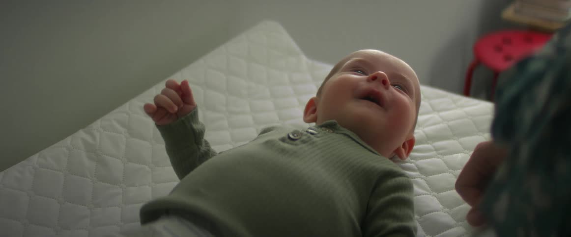 Baby laughs as mom caresses their cheek