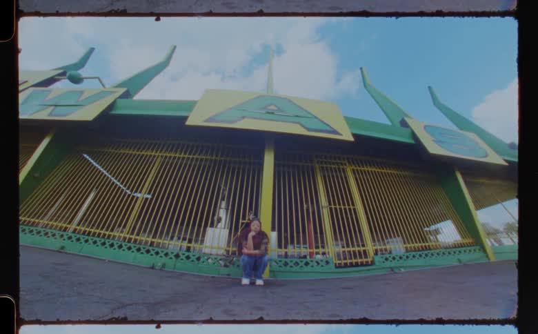 Woman crouches near business with colorful exterior under a cloudy sky