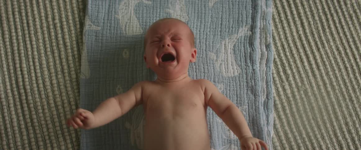 Baby moves and cries while lying on blue blanket