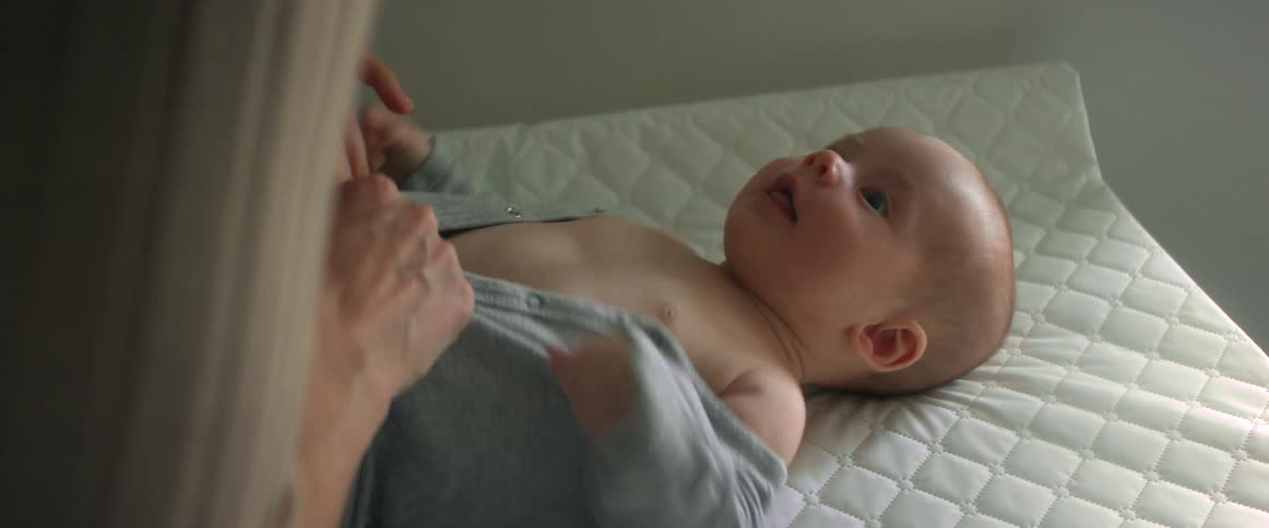 A woman plays with her baby while changing its shirt