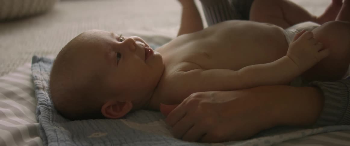 Happy baby squirming and cooing on blanket on living room floor