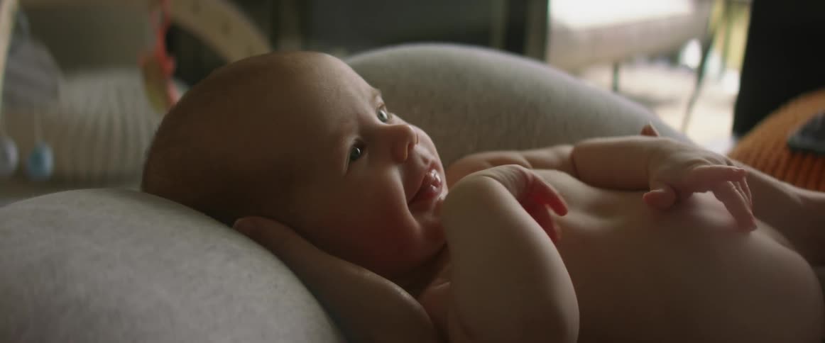 An up close of a baby with a bare belly smiling