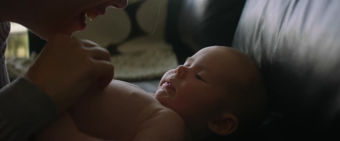 An adult woman playfully rubs and taps on her babys chest